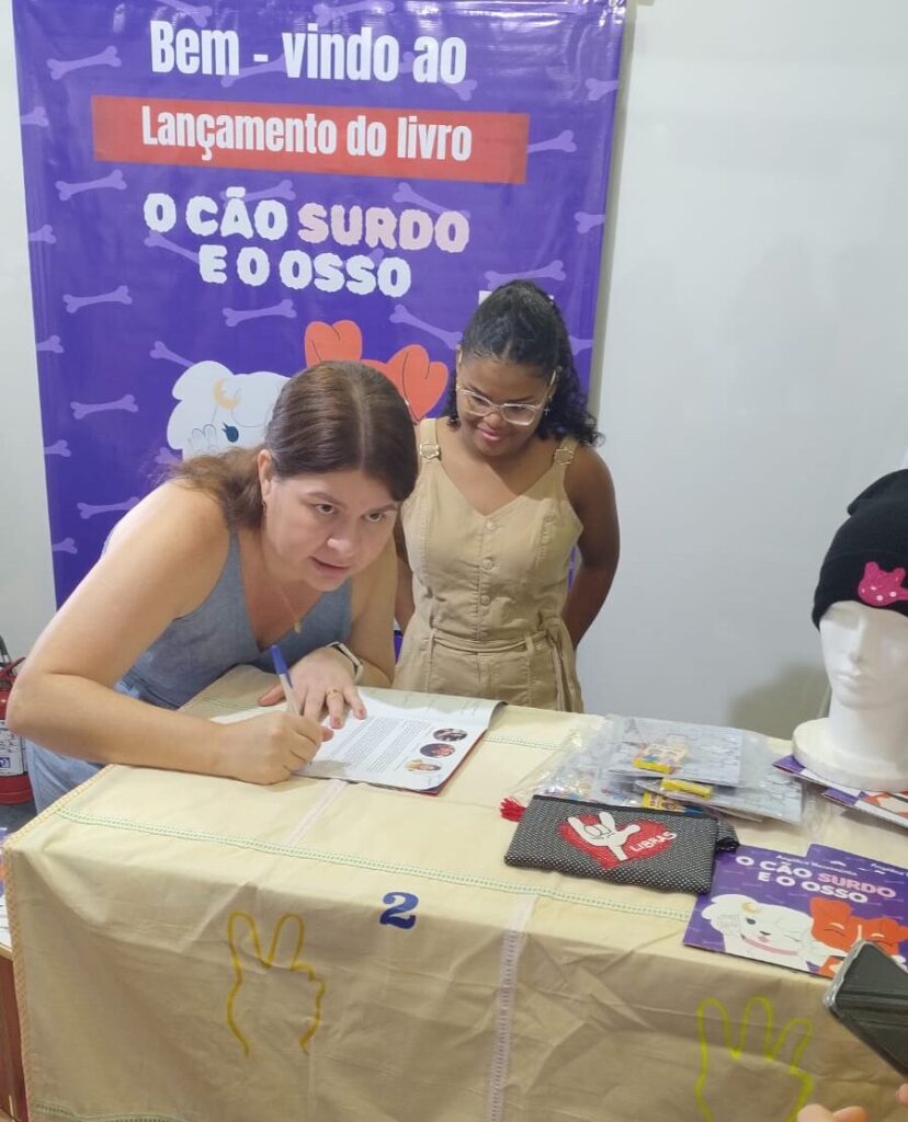 Angélica, escritora assinando o livro o cão surdo e o osso